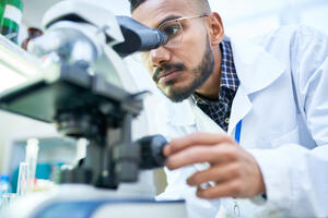 Male scientist looking through a microscope in a laboratory.